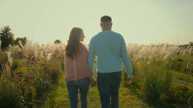 Arkaya bakan mutlu bir aile, beyaz, evli, sevgi dolu bir çift, bir kadını öpüyor, sarılıyor, sarılıyor. Romantik eşler el ele tutuşur karı öper güneşli sabah kırsal çayırlarda dolaşırlar