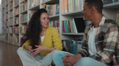 İki öğrenci Afrikalı Amerikalı erkek Latin Latin Hintli kadın tartışma kitabı okuyan kütüphane kitapçısı edebiyat edebiyatı edebiyat eğitimi alan kadın erkek edebiyatı eğitimi alan