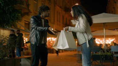 Sinirlenmiş Hintli adam konuşuyor alışveriş alışverişine bağır, alışveriş yapan bağımlı kadın torbaları tutuyor. Akşam vakti çiftler para israfı yüzünden kavga ediyor. Yüksek fiyatlar.