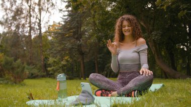 Parkta kadın etkisinde olan sporcu dışarıda. Telefon kayıtları video fitness blogu vlog sitesine uyuyor. Uzak internet kız uzak internet antrenörü spor yoga yapıyor.