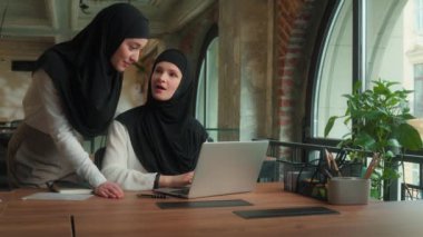 Arap Müslüman kadınlar tesettüre girmiş İslamcı kızlar iş kadınları ofis patronlarının koçluğunda dizüstü bilgisayarla şirket projesini tartışıyor stajyerlerin online iş eğitiminde kadın takım çalışmalarına yardımcı oluyor.
