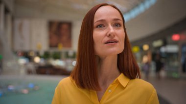 Genç, pozitif gülümseyen, beyaz, kızıl, kadın, iş kadını, tüketici, müşteri müşterisi kapalı bir mağaza, moda alışveriş merkezi eğlence merkezinde geziniyor.