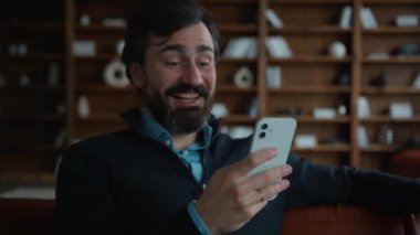 Mutlu gülümseyen Kafkasyalı orta yaşlı iş adamı müşteri girişimcisi cep telefonu internet uygulaması kullanıyor gülen işçi sosyal medyayı kullanıyor, kaşlarını kaldırıyor ve apartmanda sürpriz bir sevinç yaşıyor.