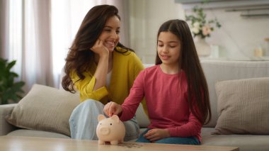 Kafkas ailesi para biriktiriyor. Yetişkin kadın anne, küçük kız çocuğuna öğretmenlik yapıyor. Para harcamaktan tasarruf ediyor.