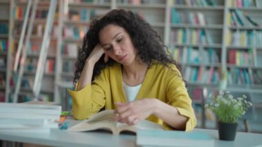 Yorgun Latin Arap bir kadın oturmuş kitap okuyor. Bilgi sınavlarına hazırlanıyor. Ders veriyor.