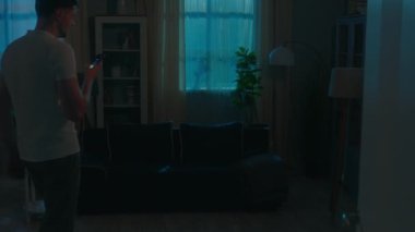 Akıllı ev aydınlatma sistemi adamı karanlık odada uzaktan aydınlık elektrik modern fütüristik ev akşamları erkek ev sahibi cep telefonu ışıkları kullanıyor uygulamayı kontrol etmek için kullanılıyor.