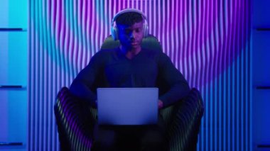 Bilgisayar programcısı, bilgisayar işçisi, kulaklıklı Afrikalı Amerikalı, erkek, dizüstü bilgisayar, internet, güvenlik oyunu, video oyunu yenilikçiliği, siber suçlar kürsüsünde oturuyor.