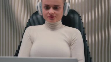 Kadın iş kadını hacker kullanıcı programcısı kulaklık takıyor koltukta dizüstü bilgisayar okuyor gelecekteki siber uzay çalışmaları iş verilerini kodluyor beyaz kız oyuncu online oyun bilgisayarı oynuyor