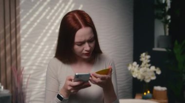 Kafası karışmış kız, beyaz kadın, ev tuvaletinde cep telefonu para transferi yanlış kredi kartı numarası dijital banka telefonu uygulaması hatası.