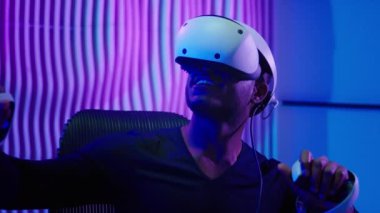 3D oyun oynayan Afrikalı erkek oyuncu VR kasklı sanal arttırılmış gerçeklik gözlükleri internet teknolojisi fütürizm siber oyunu metaevren neon fütüristik mor arka plan oyunu oynuyor