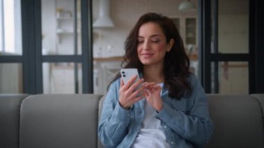 Mutlu, mutlu, mutlu, kaygısız, neşeli, beyaz kadın, evinde, kanepede gezinen, cep telefonu akıllı telefonu kullanan, sohbet eden, sosyal medya uygulaması bağımlısı, internetten alışveriş yapan.