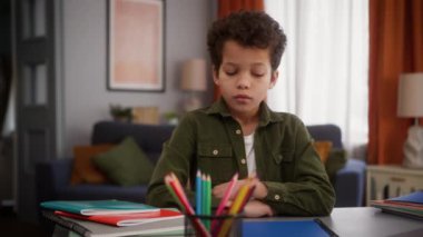 Afrikalı Amerikalı küçük oğlan çocuğu üzgün üzgün üzgün üzgün düşünceli düşünceli evde oturmuş düşünceli düşünceli ev ödevi eğitim sorunu stresli çalışmalar uzak mesafelere çalışmayı öğrenme