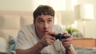 Heyecanlı Kafkasyalı erkek adam, oyun konsolu video oyunu, eğlence, kahkaha, sanal kazanan yarışma, internet yatak odası, eğlence, elektronik kontrol, siber kontrol teknolojisi.