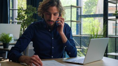 Arap bir adam, İspanyol bir işadamı, işvereni cep telefonu arama bilgilerini bilgisayardaki kontrol belgelerine, danışmanlık yapan müşteriye uzaktan kumandalı iş konsültasyonuna konuşuyor.