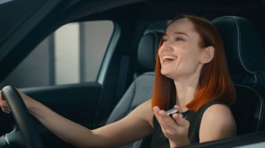 Mutlu gülümseyen beyaz iş kadını yeni arabanın içinde oturuyor gülümsüyor müşteri alıcısı kadın sürücü araba sahibi araba kuaförü araba kiralayan araba kiralayan kadın anahtar gösteriyor.