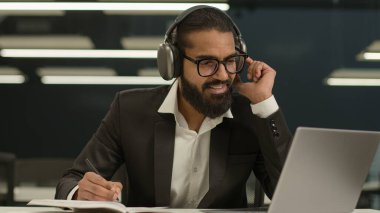 Mutlu gülümseyen 30 'lu yaşlardaki kulaklıklı Arap işadamı laptopa bakıyor. Seminer derslerini seyrediyor. Hintli iş adamının internet üzerinden yaptığı görüşme videosu.