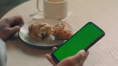 Arkaya bakan tanınmayan adam erkek müşteri ziyaretçi kafe lokantası öğle yemeği kahvesi masa başında cep telefonu faturası internet yemek siparişi alışveriş cep telefonu yeşil ekran krom anahtar yer