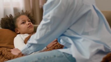 Afro-Amerikalı çocuk boğaz virüsü öksürüyor anne kızının alnına dokunuyor ana-baba hasta çocuk bakımı kadın çocuk bakımı solunum sistemi salgını mevsimsel enfeksiyon iyi değil