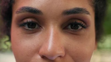 Kırpılmış görüntüyü kapat kadın yarı yüz göz kırp bayan Afrikalı kadın görüş gücü koyu renk bak şehrin lazer düzeltme göz doktorunda kameraya bakarak sağlıklı tıp sağlığını düzelt