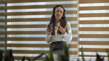 Kafkasyalı, mutlu, dans eden, ofis işkadını, mola ver. Kulaklık takıp müzik dinle. Kulaklık tak, kulaklık tak, kahve iç.