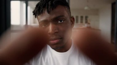 Web kamerasının bakış açısı POV ciddi Afrikalı Amerikalı adam etkileyicisi kullanıcı erkek dokunmatik ekran parmaklar ekranda kayıyor cep telefonu dokunmatik ekran büyüyen fotoğraf büyüyen evde cep telefonu bağımlısı