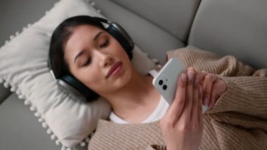 Latin Latin bayan sakin ol kanepede dinlen evde tek başına müzik kulaklıkları dinle Kafkasyalı kız kulaklıkla müzik dinleyen internetteki ses uygulaması cep telefonu bağımlısı
