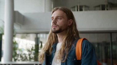 Düşünceli, ciddi, sakin, düşünceli erkek öğrencinin aklından geçeni düşünmesi üniversite öğrenim kursunda dizüstü bilgisayarın portresini tutarak öğrenme kursuna bakması.