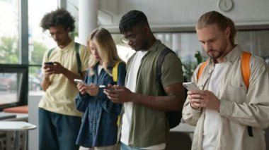 Çok ırklı grup öğrencileri, çok ırklı arkadaşlar, Afrikalı Amerikalı erkekler, Kafkasyalı kadın, lisede cihaz bağımlısı, cep telefonlarıyla video oyunu sosyal medya oyunu oynuyor.