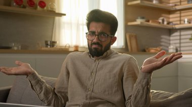 Hintli Arap Müslüman adam mutfakta serbest çalışan iş adamı laptopçu evde omuz silkiyor. Erkek müşterinin kafası karışmış. Şüphe yok ki şüpheye yer yok.