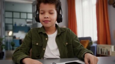 Komik Afro-Amerikalı çocuk çocuk evde eğleniyor. Duraklıyor. Kulaklıklarda müzik dinliyor.