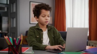 Afro-Amerikalı erkek çocuk çocuk öğrenci öğrenci evde bilgisayar yazarak çalışıyor uzaktan öğrenim ev ödevi öğreniyor online eğitim interneti kullanarak oyun oynuyor.