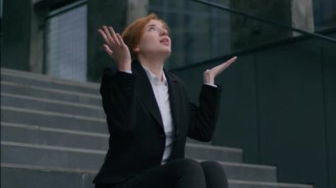 Stresli, üzgün, Kafkasyalı iş kadını kadın işkadını işsiz, merdivenlerde oturan, el ele tutuşan, hayal kırıklığına uğrayan, şehir dışındaki işsizlik sorunları yüzünden işten atılmış.