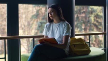 Kafkasyalı, düşünceli, düşünceli, kız öğrenci, kız öğrenci, kız öğrenci, şehir dışında, üniversite fakültesi yakınlarında, elinde defter tutarak eğitim görüyor.