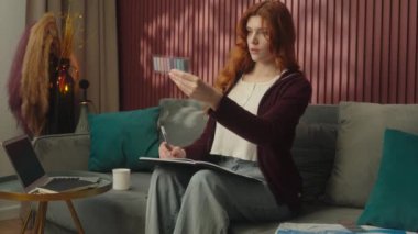 Kafkasyalı kadın ev sahibi kadın sanat tasarımcısı, yaratıcı dekoratör kanepe üzerinde çizim defterleri hazırlıyor. Renk örneklerine bakıyor. Renk tonlarını seçin.