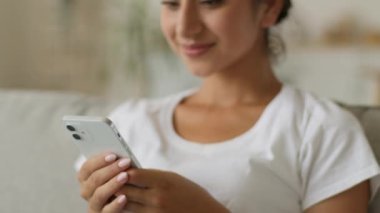 Mutlu gülümseyen Hintli kadın evde akıllı telefon kullanıyor. Cep telefonu bağımlısı Arap kız elinde cep telefonu tutuyor. Sosyal medyada internet üzerinden alışveriş yapıyor.