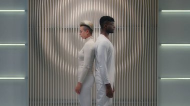 İki çok ırklı insan, meta-ırk oyuncuları, beyaz kadın kadın kadın, Afro-Amerikan erkek adamla el ele tutuşup kamera siber uzay fütüristik oyununa baktılar.