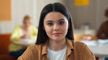 Okul akademisi üniversite dersi gülümseyen beyaz tenli güzel öğrenci kız kız öğrenci kız öğrenci kız öğrenci portresi sınıf arkadaşlarının eğitim çalışmalarını kameralara bakarak öğrenme portresi