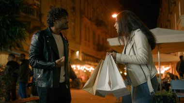 Sinirlenmiş Hintli adam konuşuyor alışveriş alışverişine bağır, alışveriş yapan bağımlı kadın torbaları tutuyor. Akşam vakti çiftler para israfı yüzünden kavga ediyor. Yüksek fiyatlar.