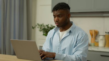 Afrikalı etnik adam serbest çalışan erkek, çift ırklı erkek işadamı, ev sahibi, bilgisayarlı ev sahibi, uzak mesafelere çalışıyor, bilgisayar alışverişi yapan internet mutfaklarında sohbet ediyor.