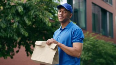 Afro-amerikan postacı postacı üniformalı kurye şehir çalışanı teslimat erkek holding sipariş alışveriş paketi teslim mutlu postacı kağıt torba gösteren gülen