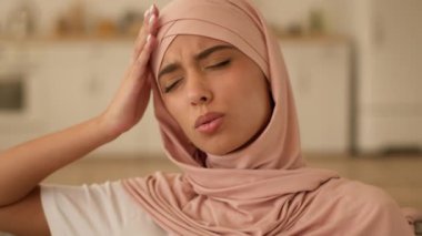 Sağlıksız, sağlıksız, kötü, acı çeken, üzgün, Müslüman kadın, evde Arap, baş ağrısı, baş ağrısı, migren, kan basıncı, sağlık sorunları.