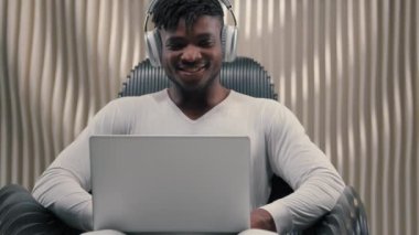 Mutlu gülümseyen, Afro-Amerikan erkek oyuncu programcı, iş adamı iş adamı iş adamı laptop internet üzerinden oyun modern fütüristik oda kullanarak siber uzay kulaklığı takıyor.