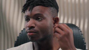 Sakin Afrikalı Amerikalı etnik erkek erkek modern fütüristik oda kablosuz kulaklık müzik dinleyen kulaklık ses kalitesi teknoloji internetten müzik dinleyen internet ve müzik dinleyen müzik