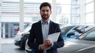 Kafkasyalı bir adam kamera satıcısına bakıyor araba satıcısı araba satıcısı araba satıcısı araba galerisi danışmanı gülümseyen profesyonel yönetici gösteri odası portresi mutlu bir adam seçmeme yardım ediyor.