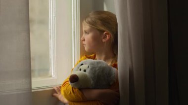 Mutsuz, küçük beyaz kız oyuncak ayıya sarılıyor çocukluk kurbanı mutsuz çocuk çocuk depresyonu genç kız hayal kırıklığı pencere görünümlü düşünceli hüzünlü boşanma çocuğu