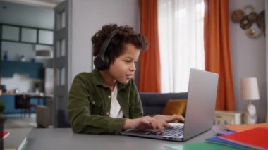 Komik küçük Afrikalı çocuk çocuk oyun masasında oyun oynayan internet oyun bilgisayarı başarıyı kazandı kulaklık takarak zaferi kazandı zaferi kutlayın
