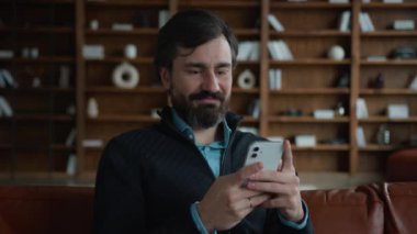 Gülümseyen Kafkasyalı erkek, olgun iş adamı psikolog, psikolog, cep telefonu kullanıcısı akıllı telefon, online uygulama, gezinen sosyal medya, ofis içi sohbetleri.