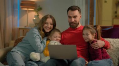 Kafkas aile ebeveynleri kanepe akşam evinde küçük kızlara bilgisayar kullanmayı öğretiyor. Anneler babalar kız kardeşlere bilgisayar eğitimi velayetini online alışveriş ebeveyn kontrolü konusunda yardım ediyor.