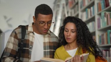 Latin kökenli beyaz kadın Afrikalı Amerikalı erkek kütüphanesi kitap eğitimi sınavı hazırlığı çalışma takımı konuşma üniversite ders kitabı öğrencilerinin kitap kurdu sohbetleri hakkında konuşuyor.