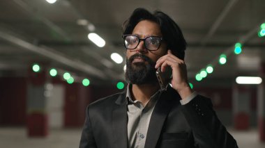 Duygusal Hintli erkek işadamı. Cep telefonuyla konuşan işadamı. Yeraltı otoparkında iş görüşmesi.